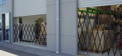 A black XPANDO barrier from E S Barriers installed at a commercial building's roller door to secure the entry.