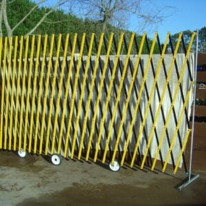A high visibility yellow XPANDO portable barrier from E S Barriers with wheels for easy mobility in outdoor environments.